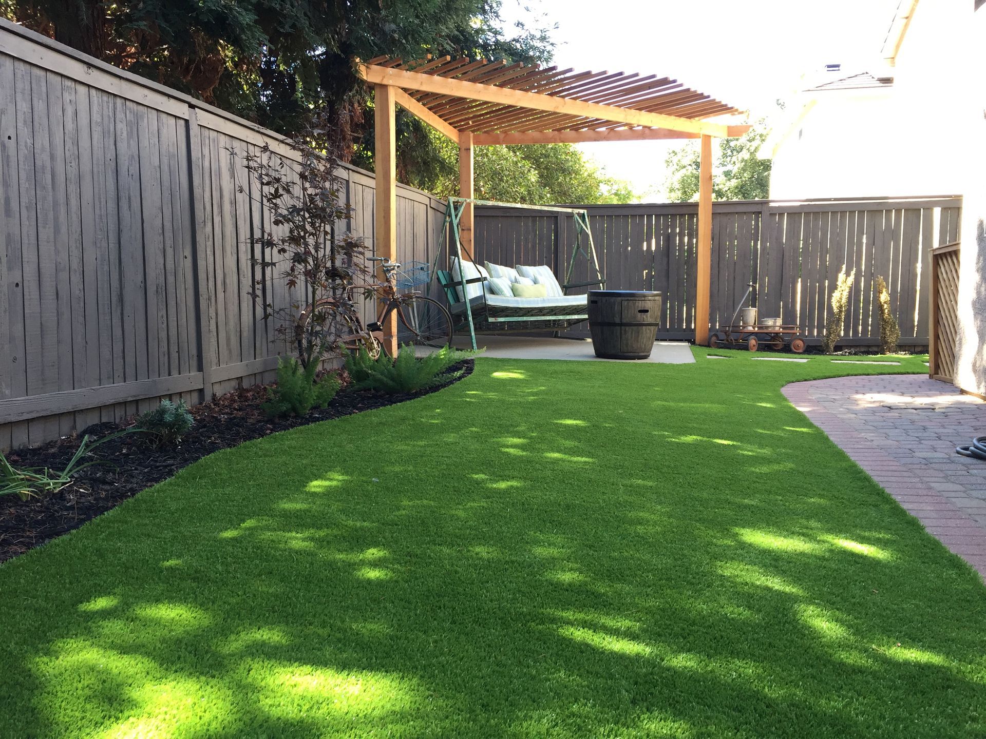 A backyard with a pergola and a swing.