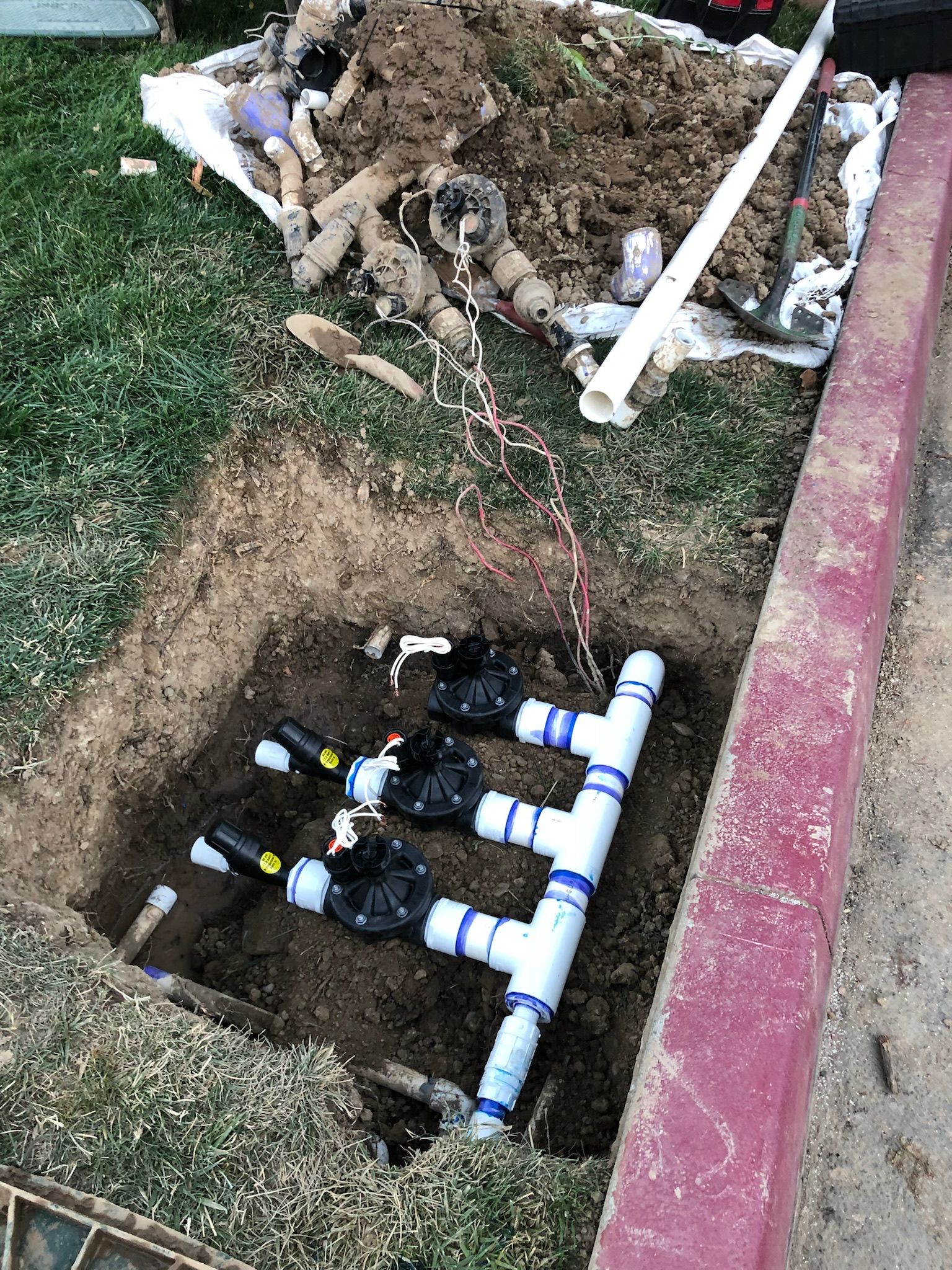 A sprinkler system is being installed in a hole in the ground.