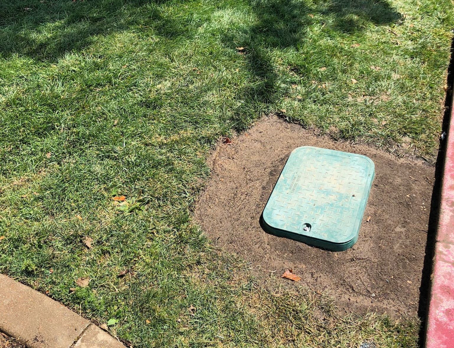 A green box is sitting in the middle of a lush green field.