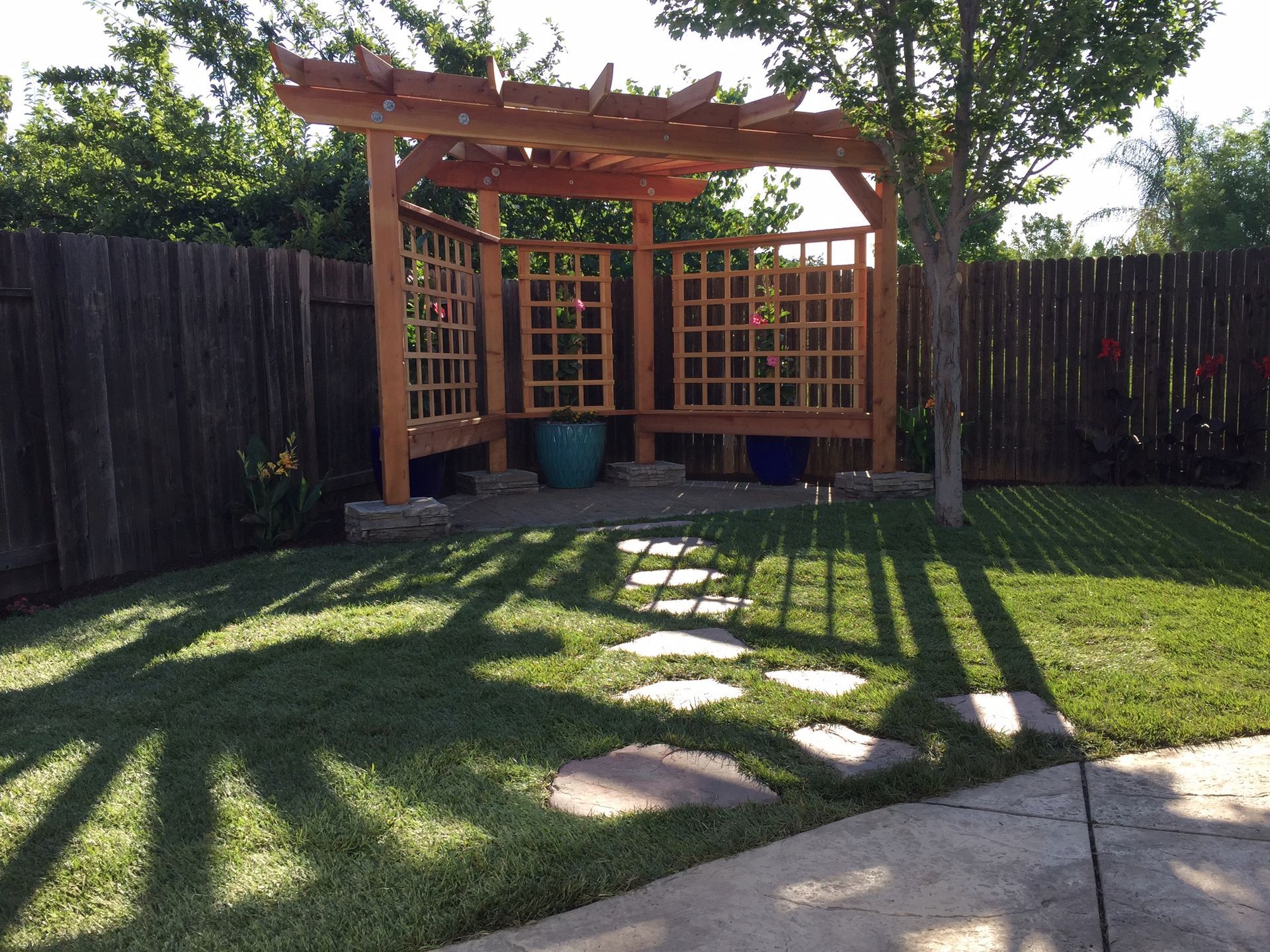 A backyard with a wooden pergola and a fence