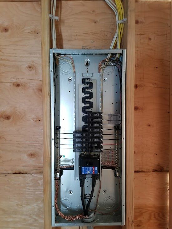 A electrical box is hanging on a wooden wall.