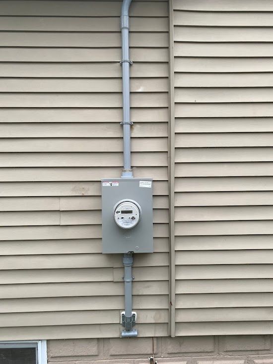 A meter is attached to the side of a house.