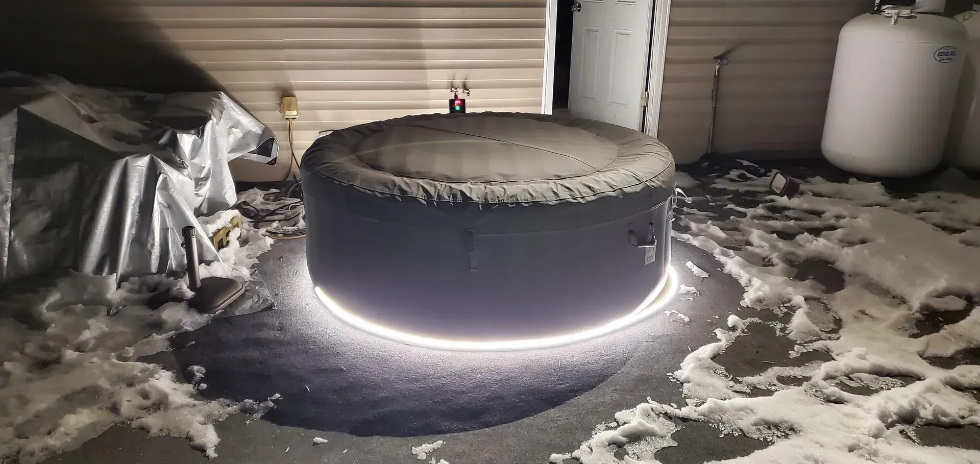 A hot tub is sitting on the ground in a garage with a light coming out of it.