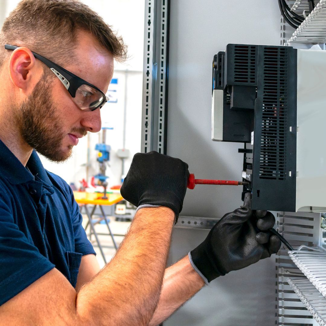 A man wearing glasses and gloves is working on an electronic device
