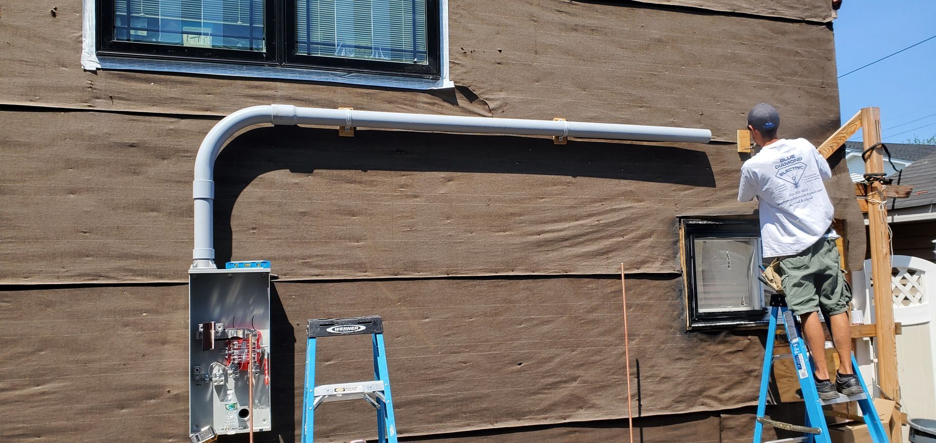 A man is standing on a ladder on the side of a building.