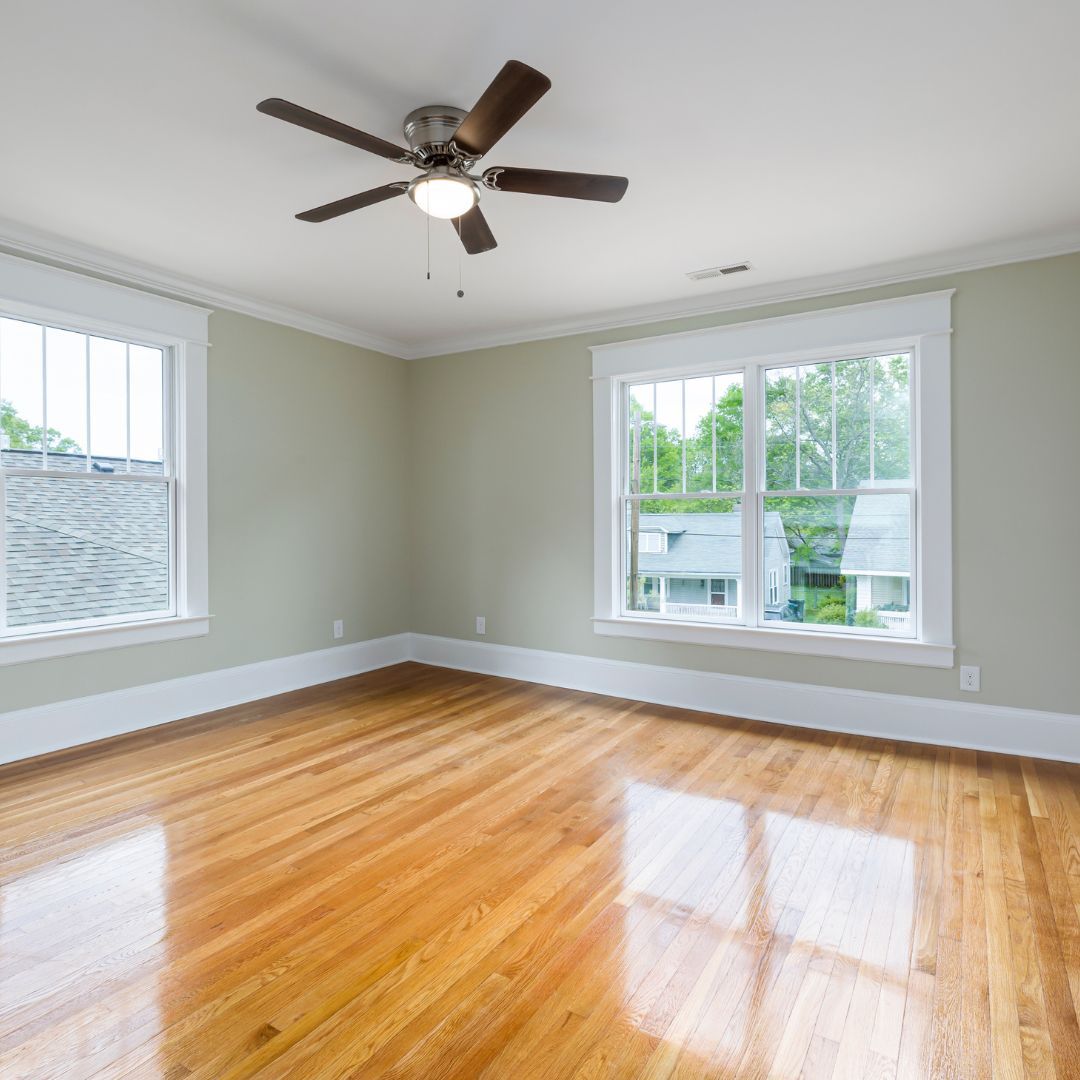 An empty room with hardwood floors and a ceiling fan.