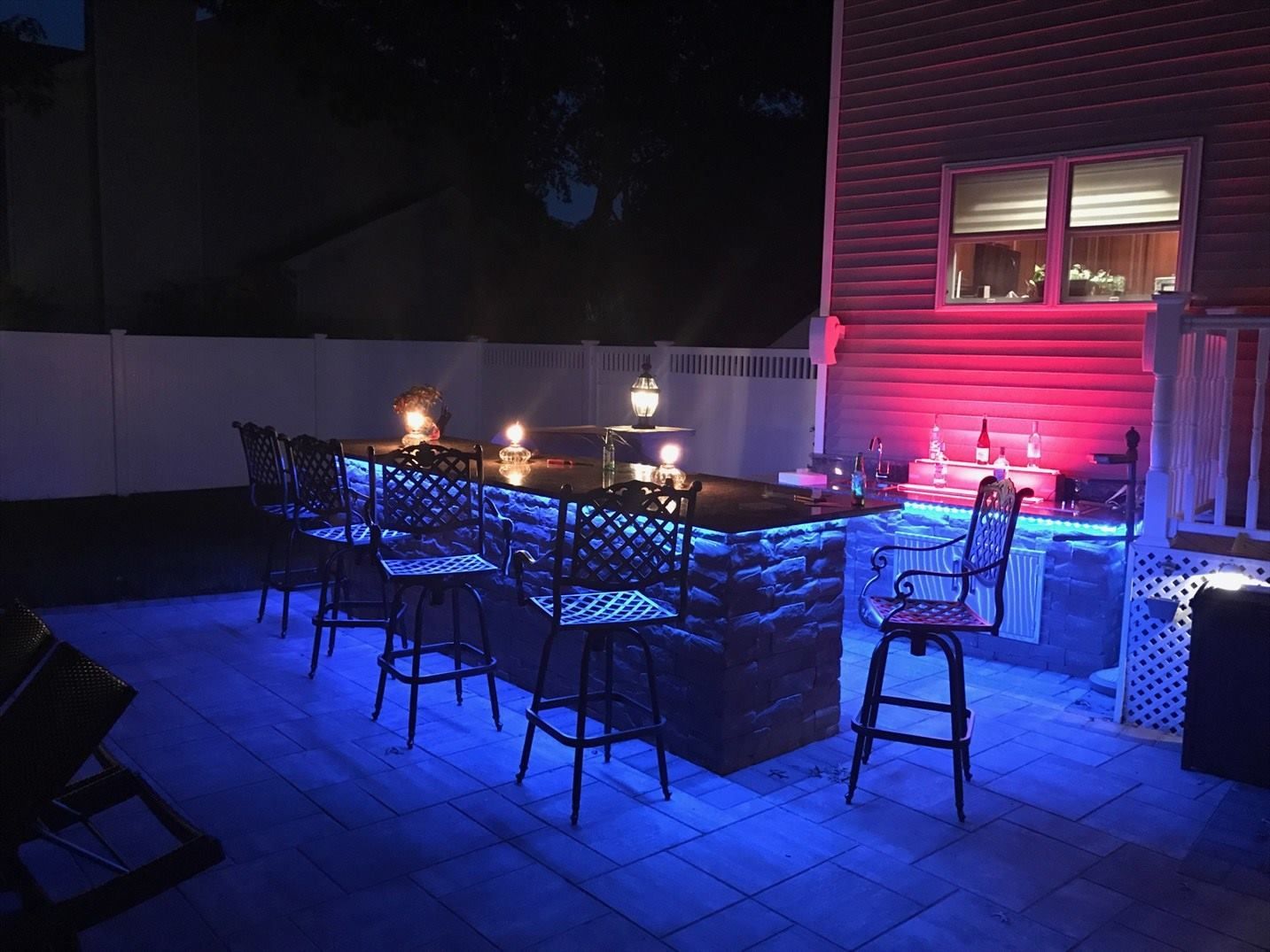 A patio with a bar and chairs lit up at night.