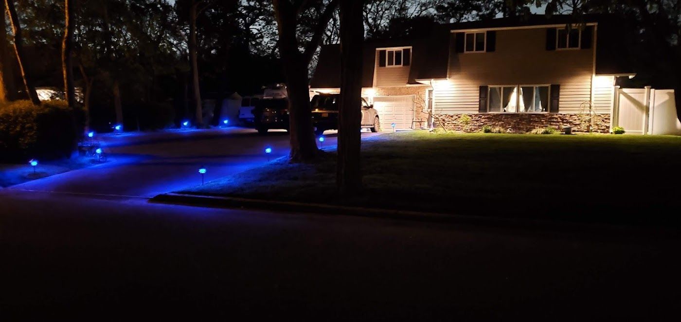 A house is lit up at night with blue lights in the driveway.