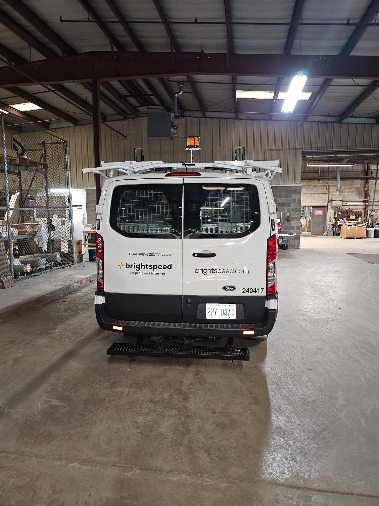 White work van, rear view, parked in warehouse, with ladder rack, back door windows.