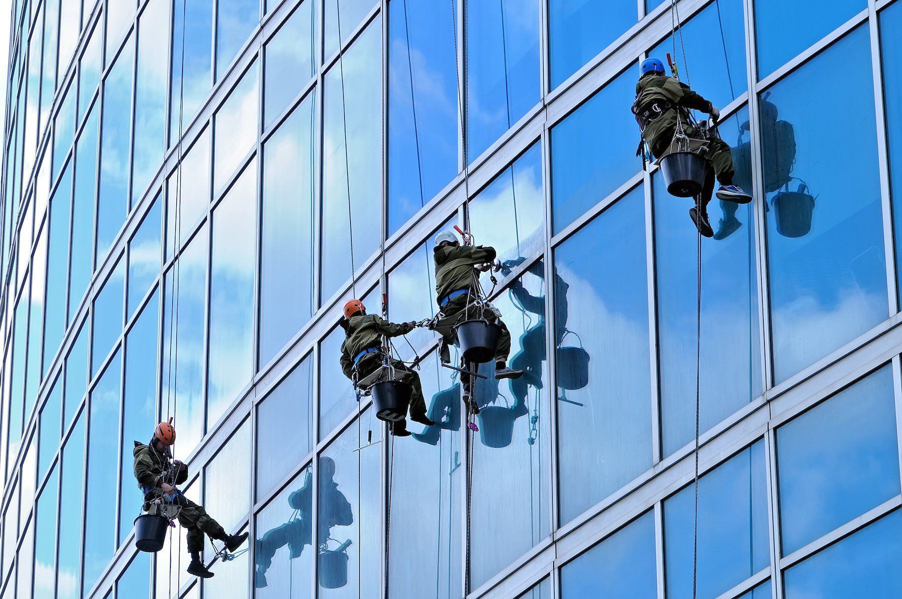 A skilled window cleaning team working diligently to clear grime and dirt from the windows of a tall urban skyscraper.