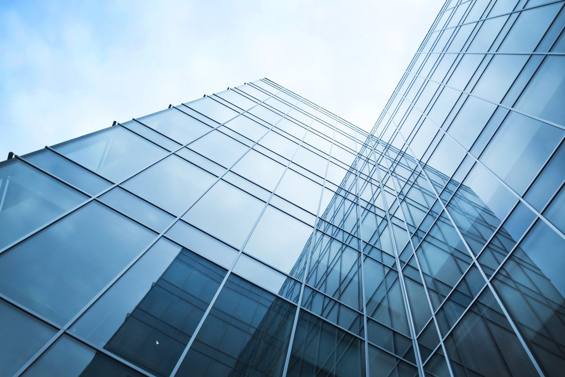 Looking up at a tall glass building with a blue sky in the background