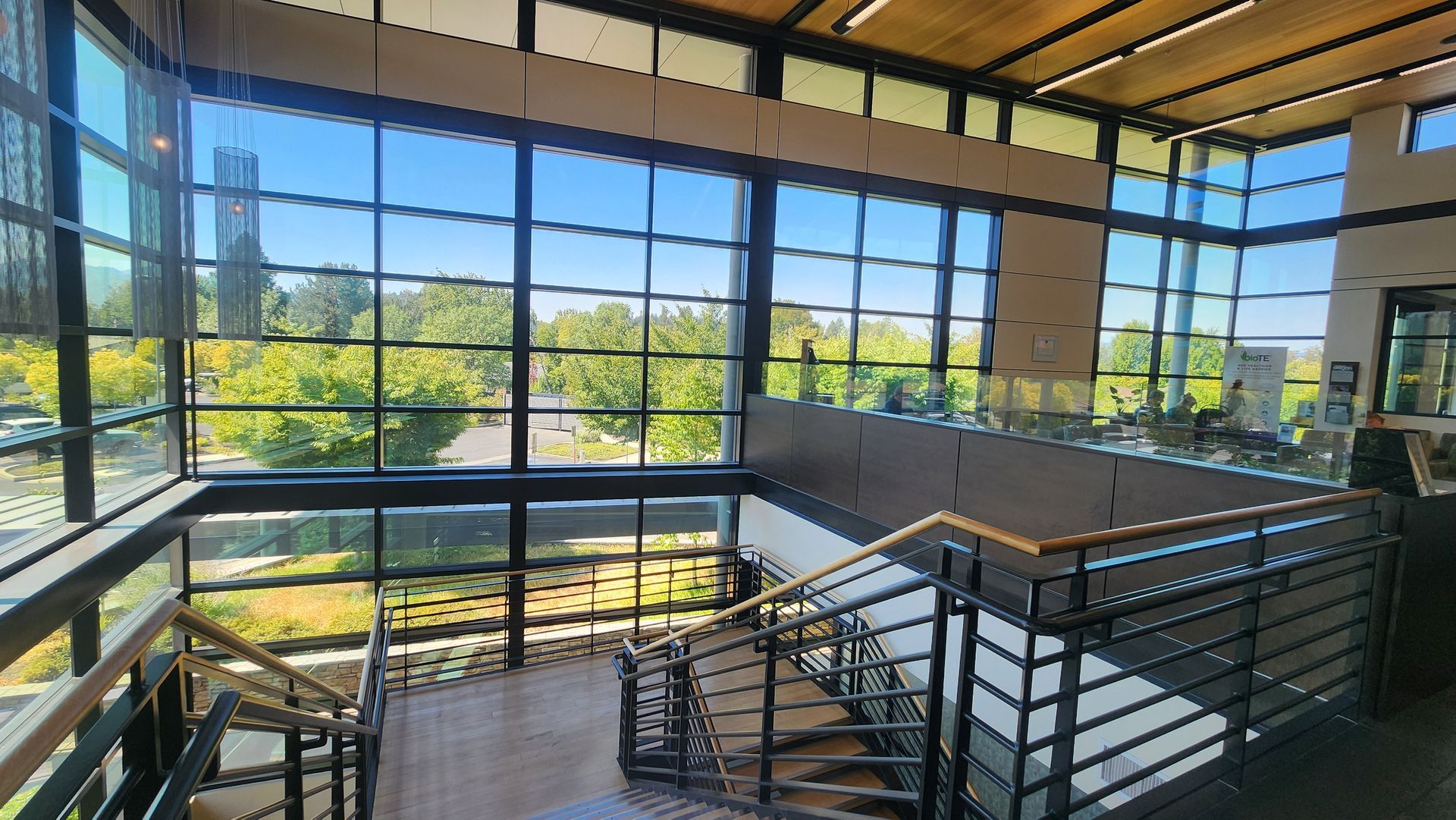 Interior view with staircase, large windows overlooking trees and outside.