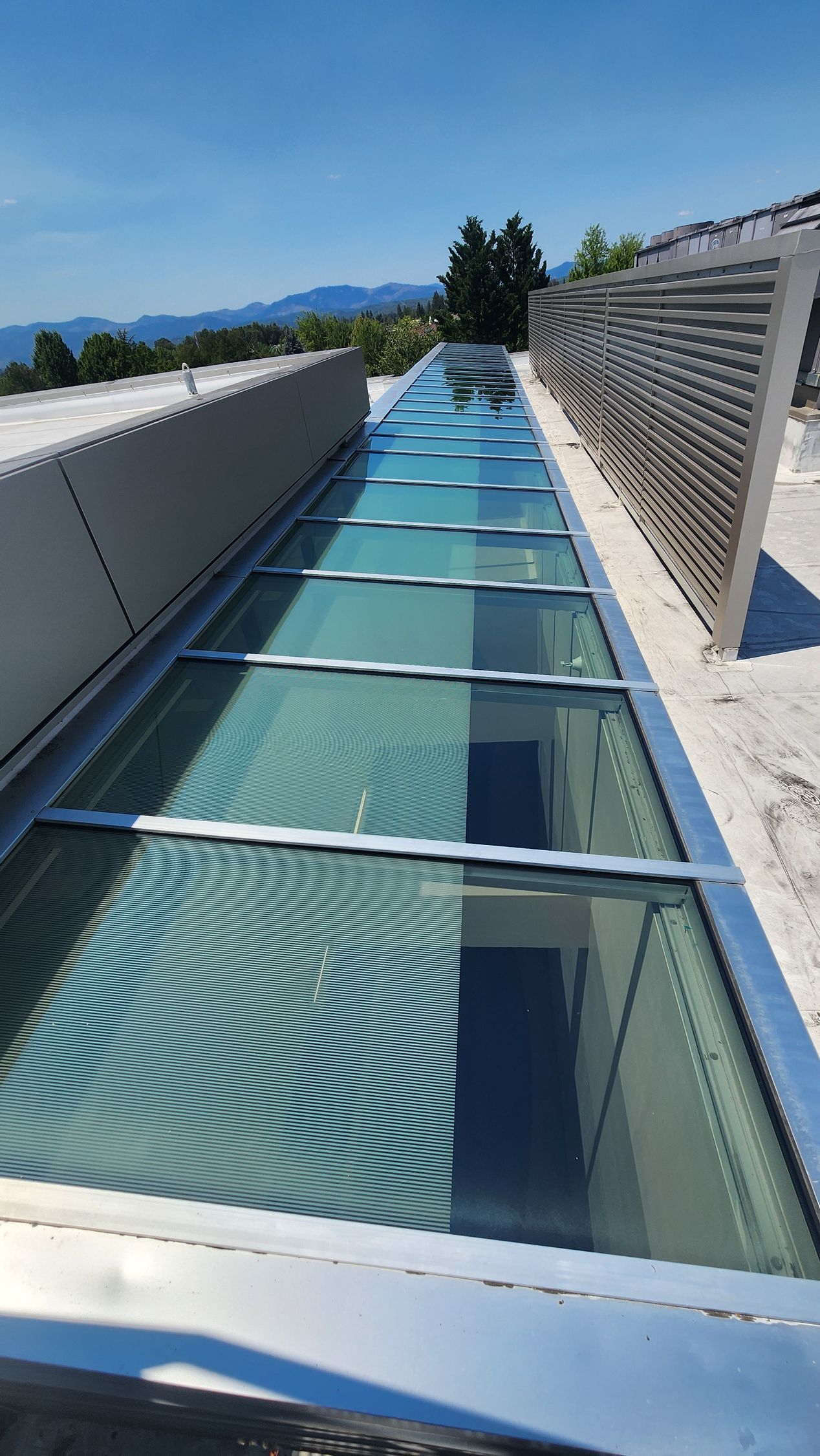 Skylight on a building rooftop; long, rectangular shape with multiple panes of glass and metal framing.