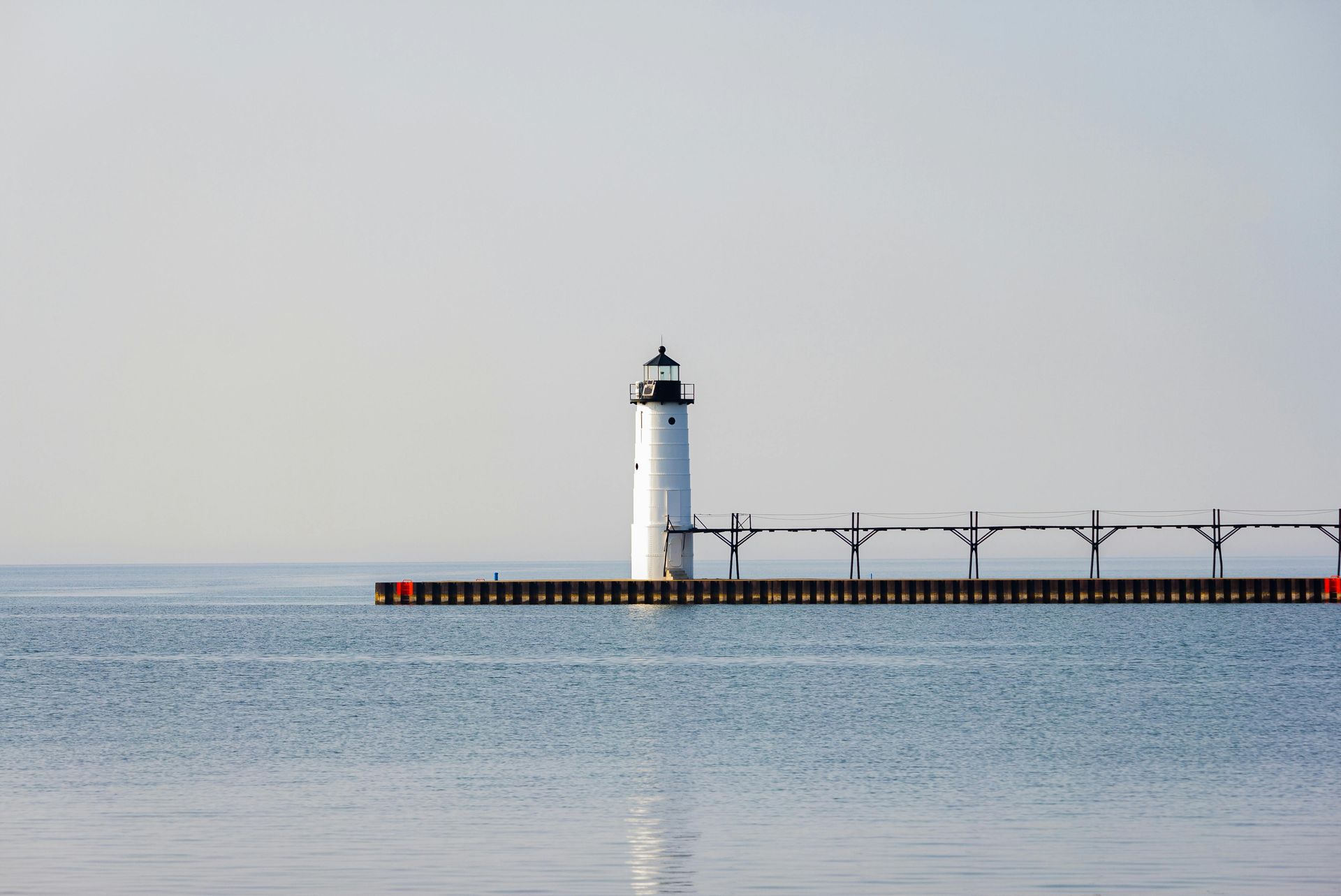 A lighthouse on a pier in the middle of the ocean