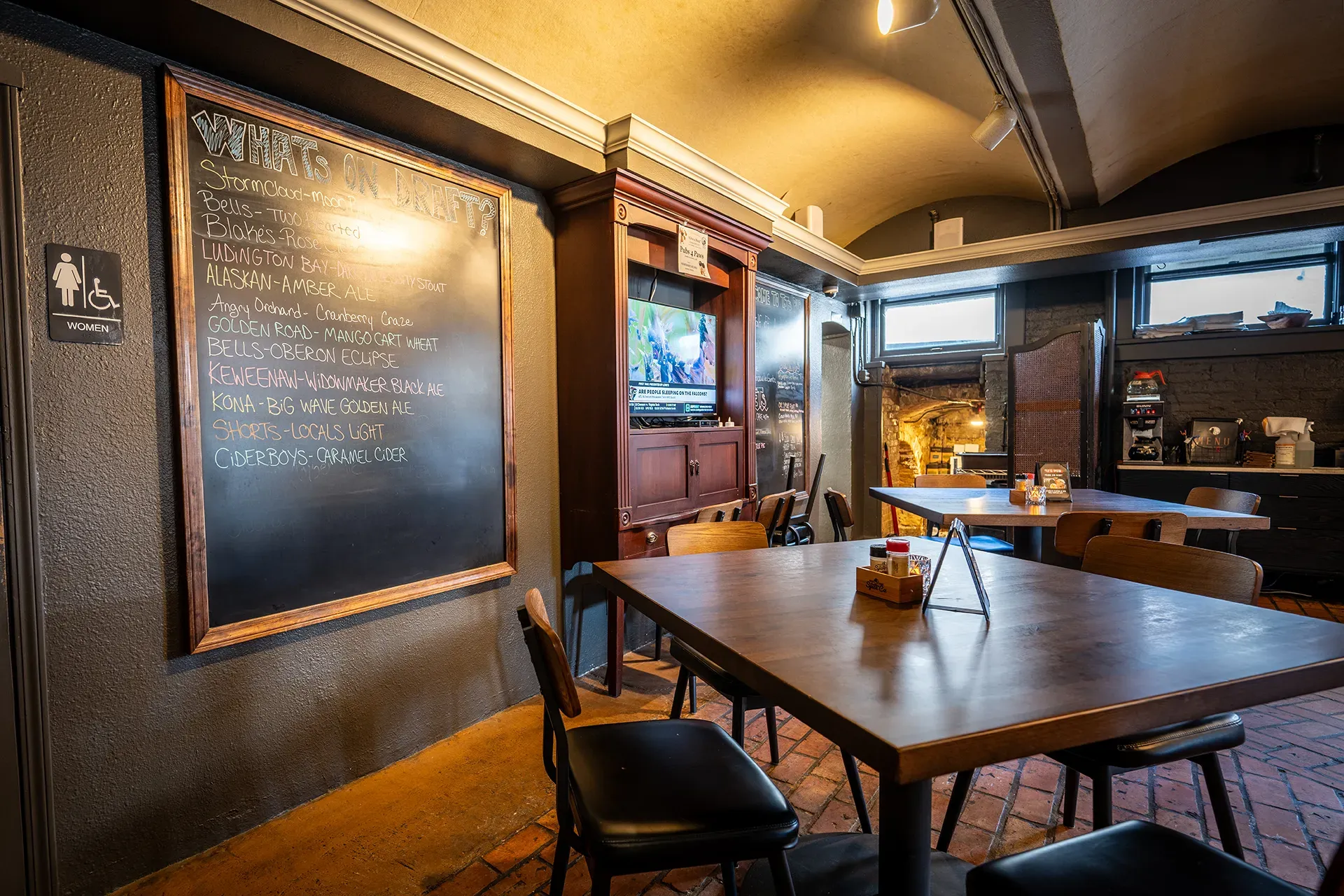 A restaurant with tables and chairs and a blackboard on the wall.