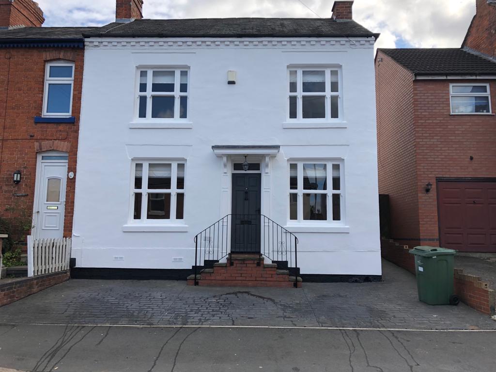 This is a picture of the outside of a house in Wigston which has been painted white with a grey painted door