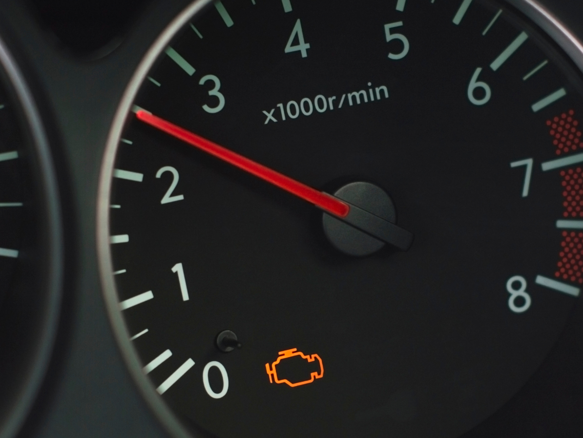 A car tachometer showing an engine speed of approximately 2,800 RPM with an illuminated yellow check engine light.