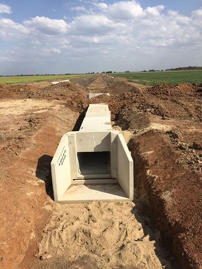 A concrete tunnel is being built in a dirt field.
