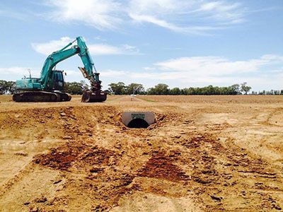 An excavator is digging a hole in the dirt in a field.