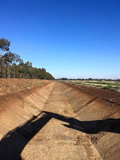 A shadow of a person is cast on a dirt road.