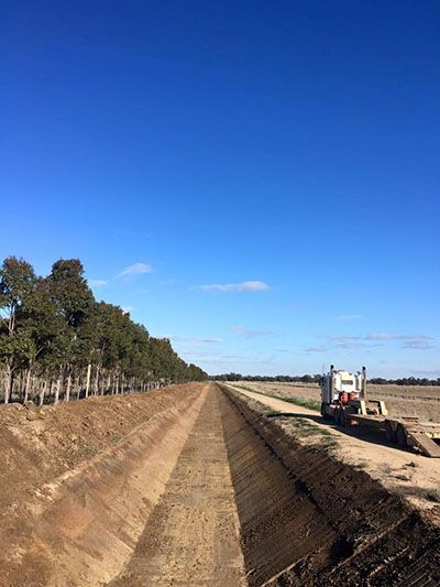 A truck is parked on the side of a dirt road.