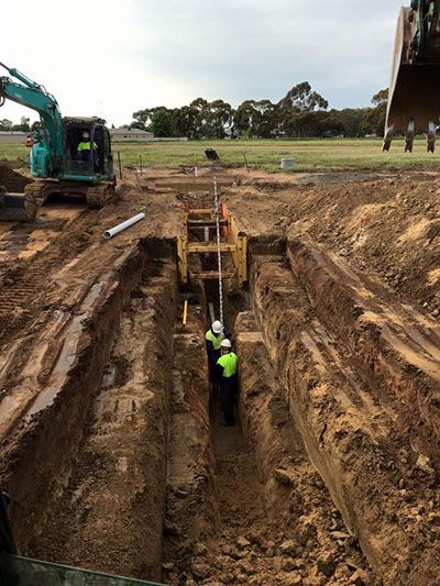 A group of construction workers are digging a trench in the dirt.