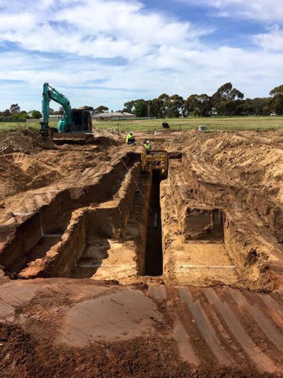 A large excavator is digging a trench in the dirt.