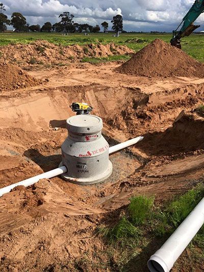 A pipe is being installed in the dirt in a field.