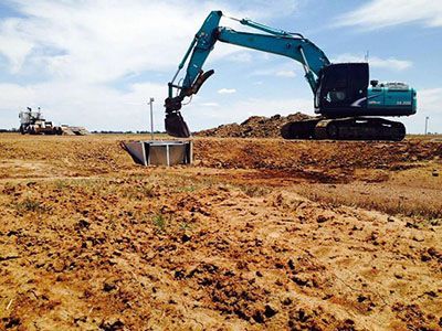 A large excavator is digging a hole in a dirt field.