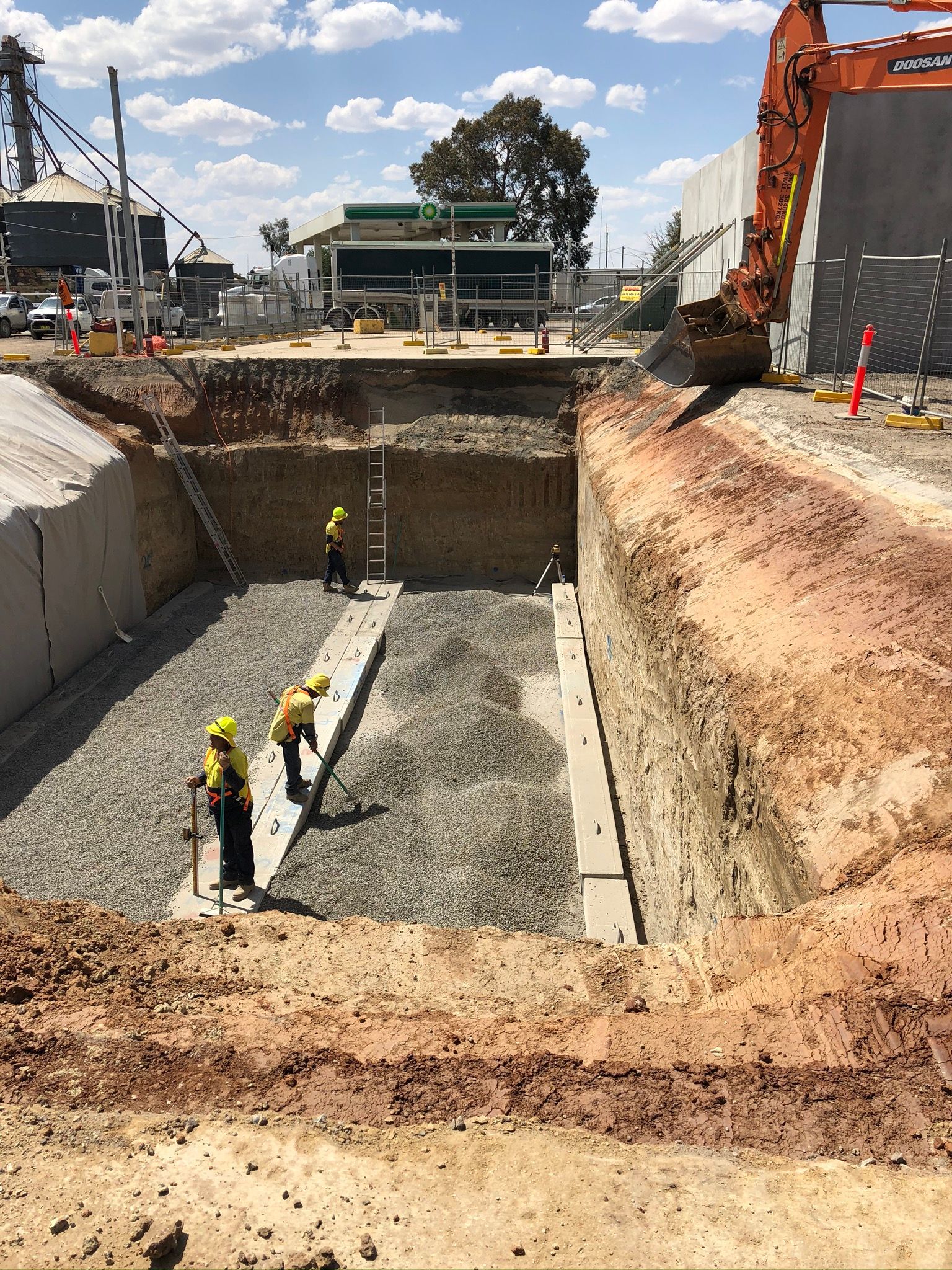 A group of construction workers are working on a large hole in the ground.