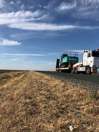 A semi truck is driving down a road next to a field.