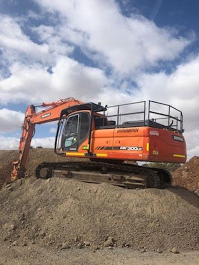 A large orange excavator is sitting on top of a pile of dirt.