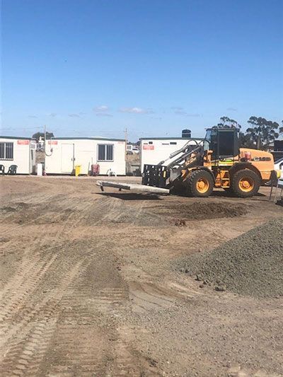 A bulldozer is parked in a dirt lot in front of a building.