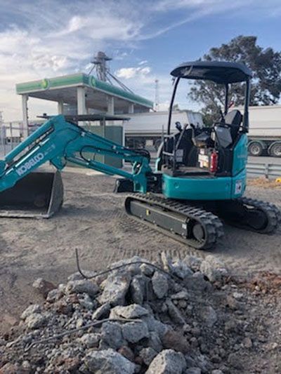 A blue excavator is sitting on top of a pile of rocks.