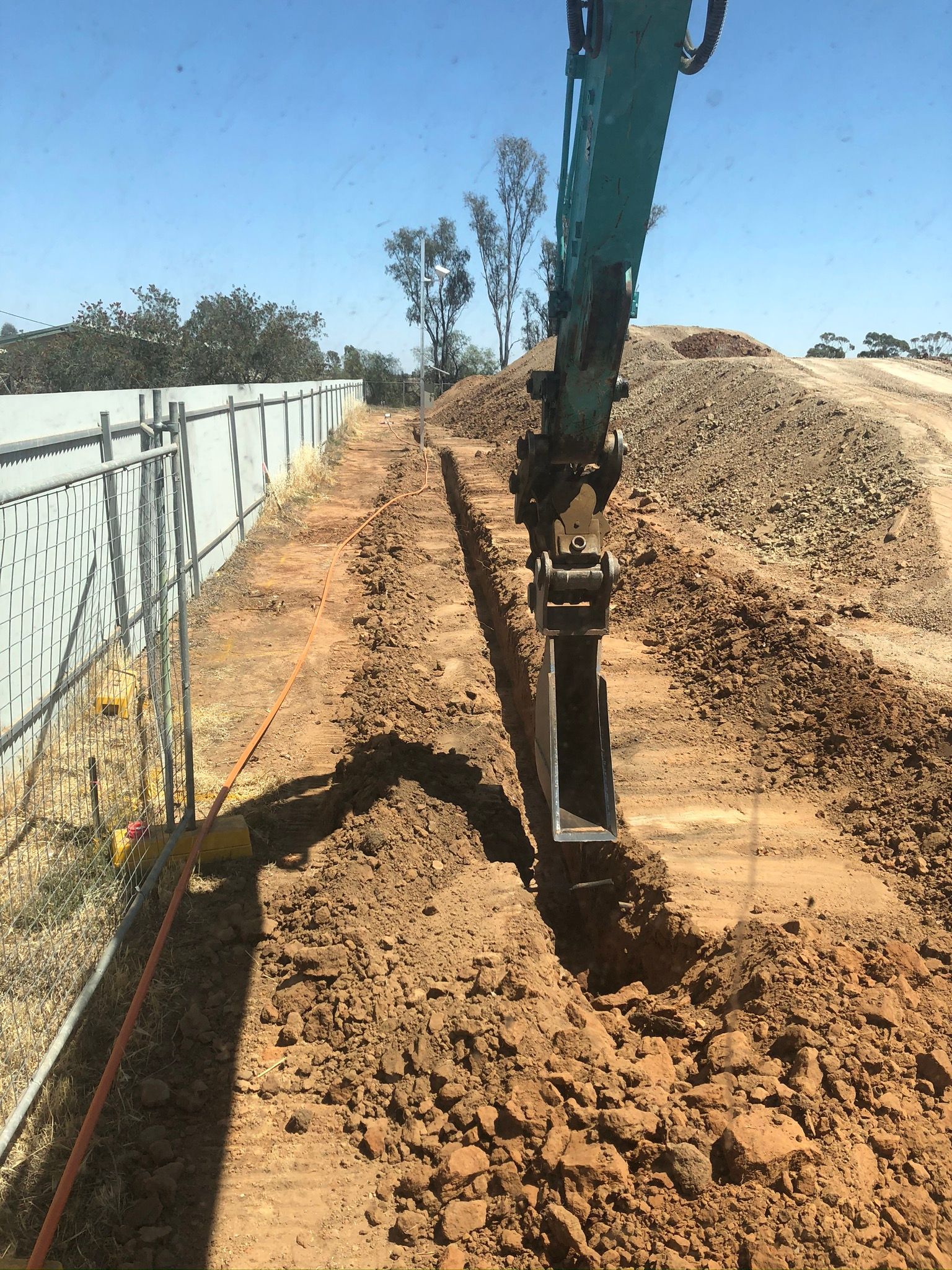 A large excavator is digging a trench in the dirt.