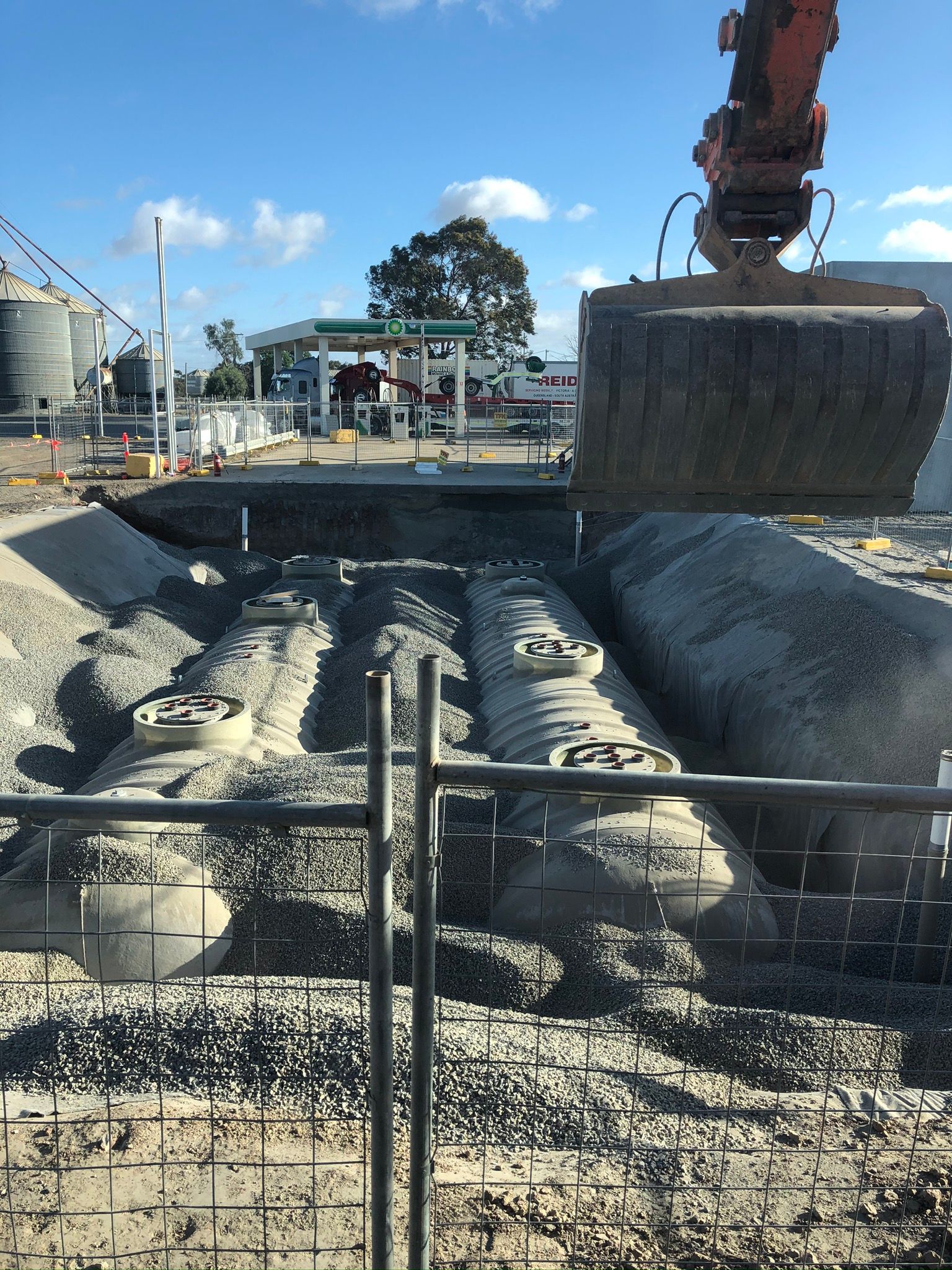 A construction site with a fence and a large excavator.
