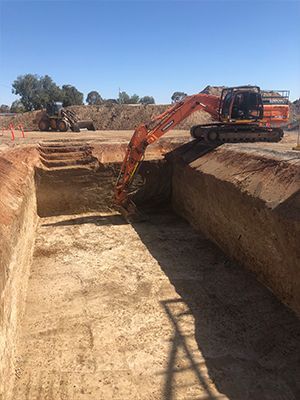 A large excavator is digging a hole in a dirt field.