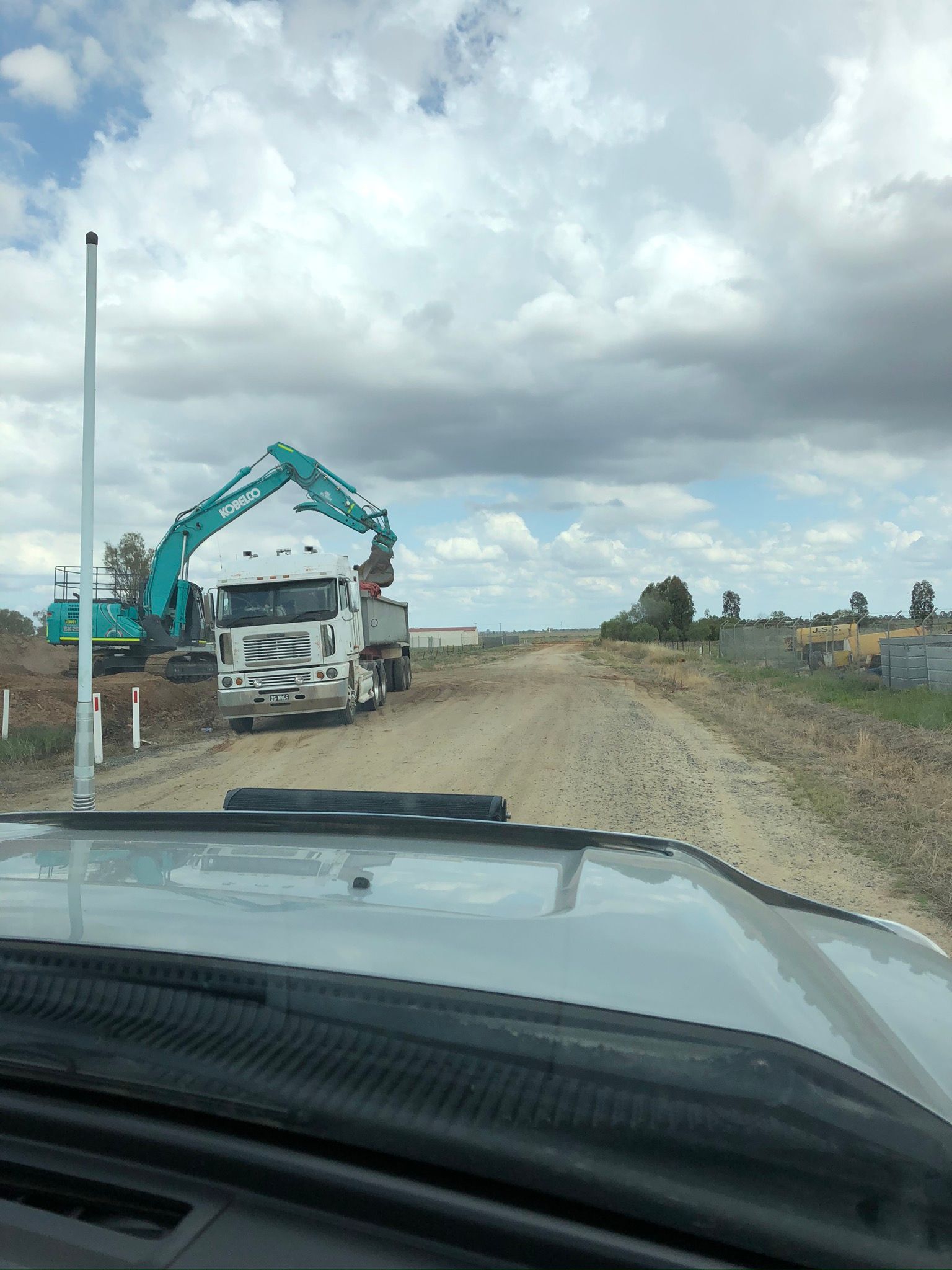 A truck is parked on the side of a dirt road.