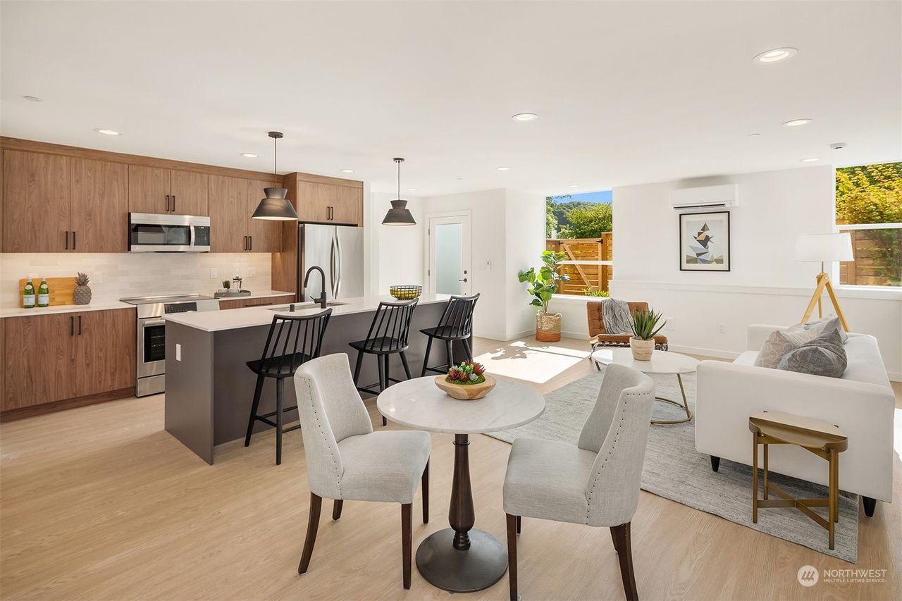 A living room with a dining table and chairs and a kitchen.