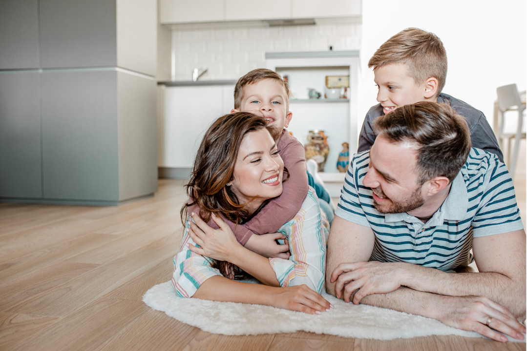 A family is laying on the floor in their new home.