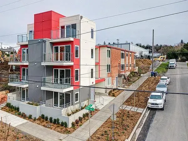 An aerial view of a row of apartment buildings with cars parked in front of them.