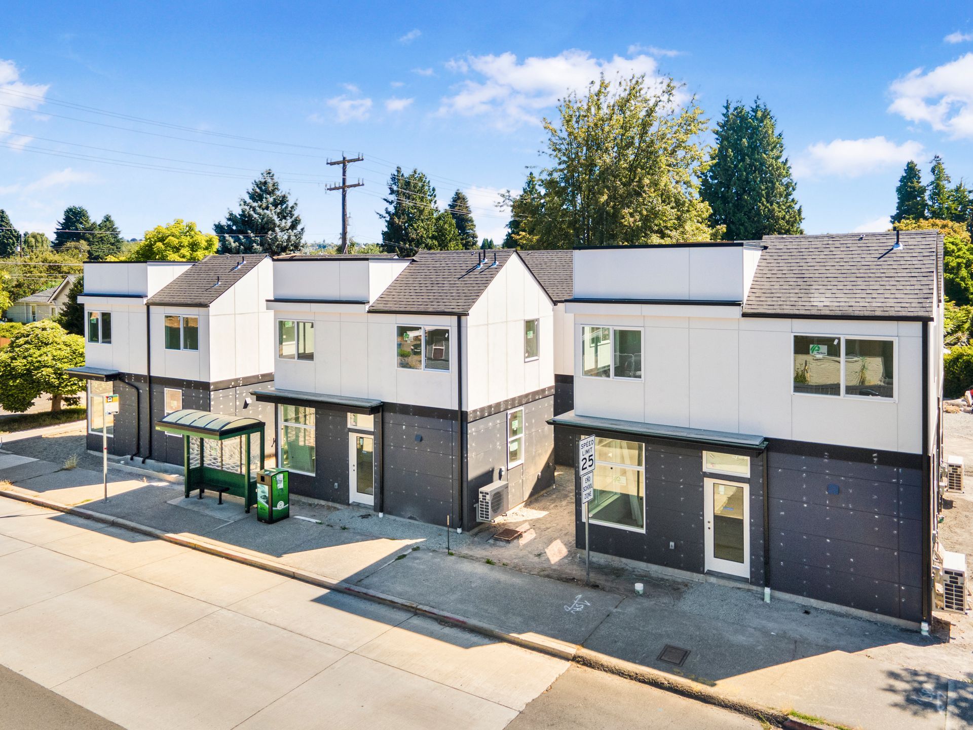 An aerial view of a row of houses with a bus stop in front of them.