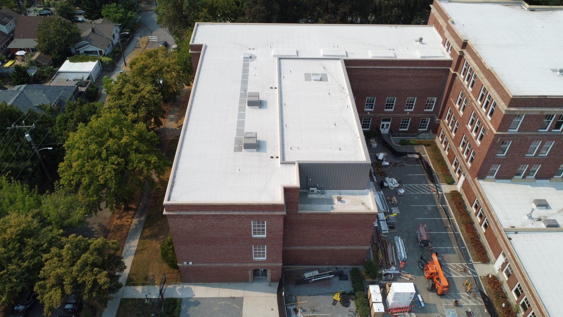 An aerial view of a large brick building with a white roof.