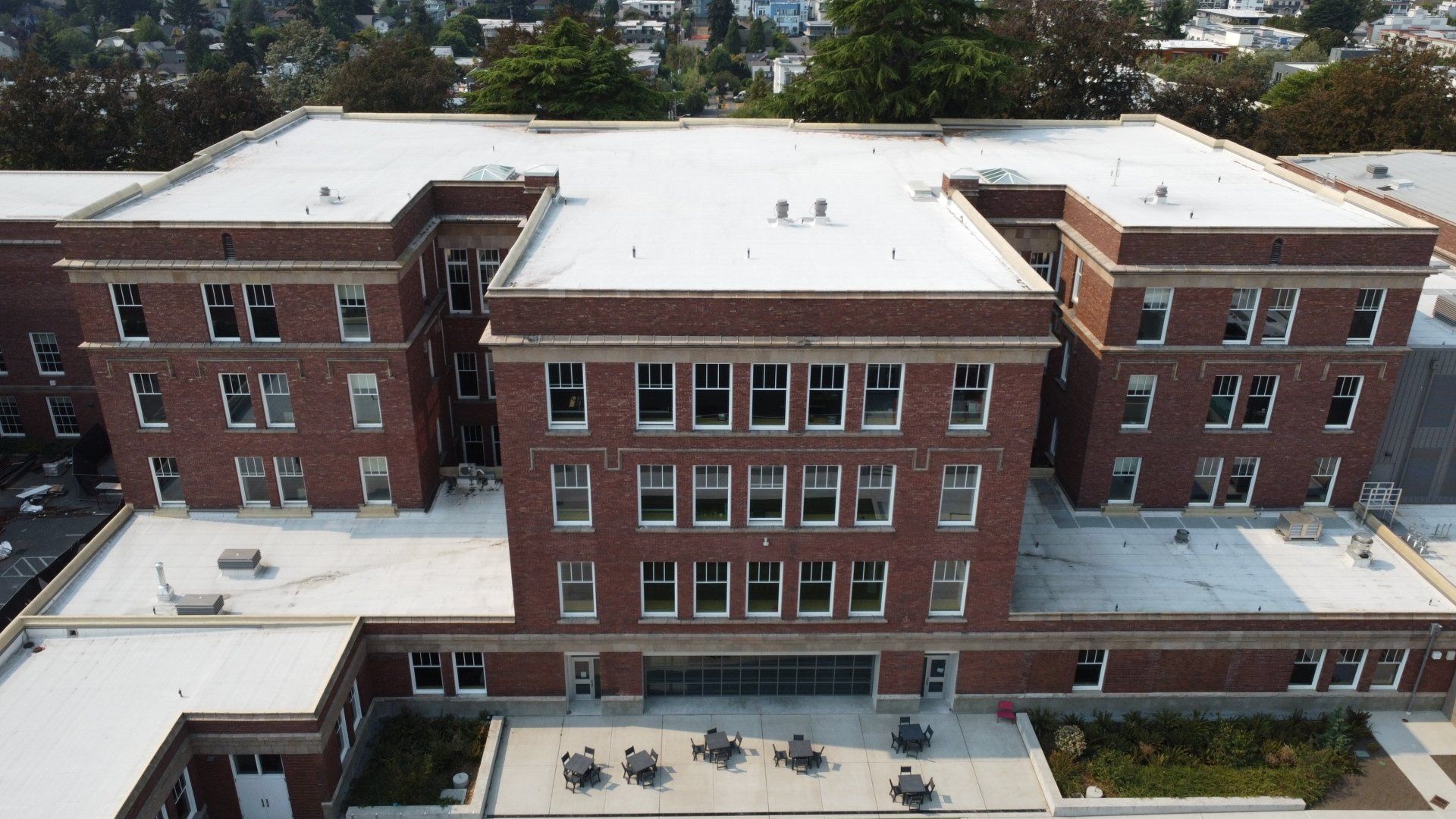 An aerial view of a large brick building with a white roof