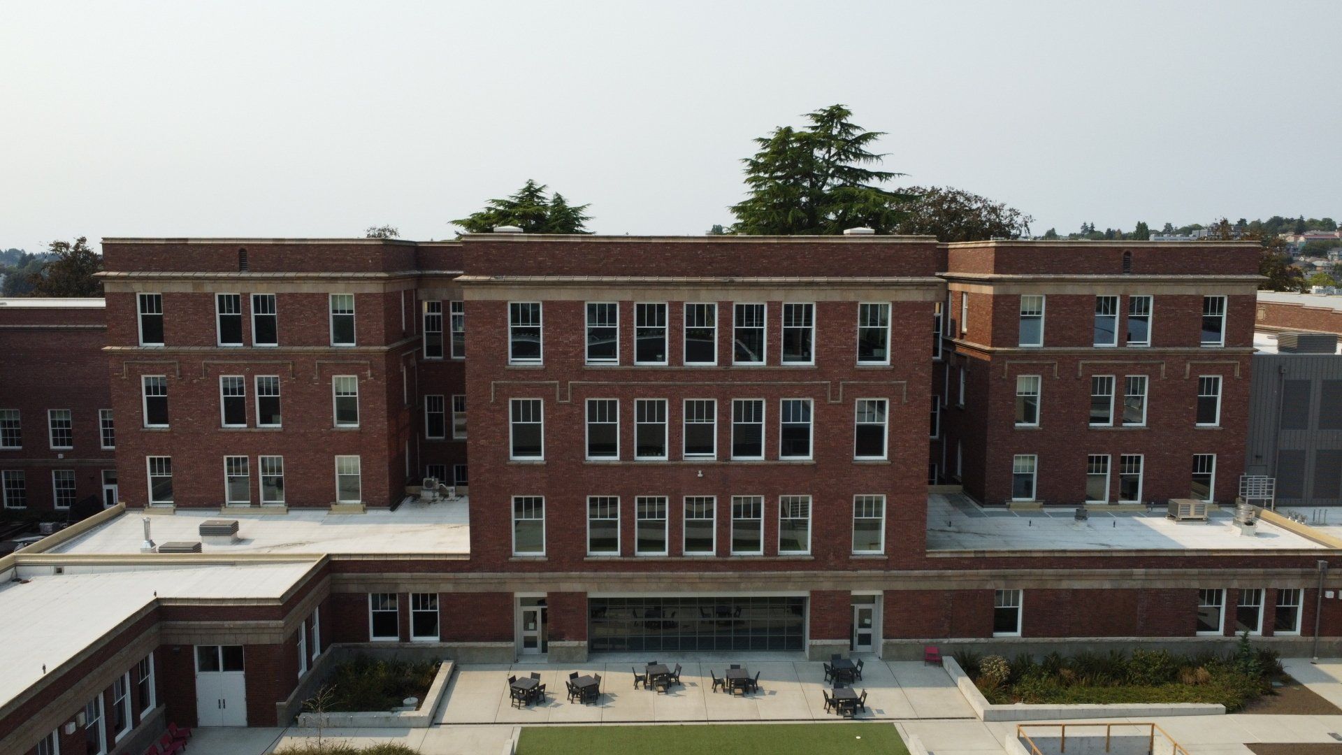 An aerial view of a large brick building with a white roof