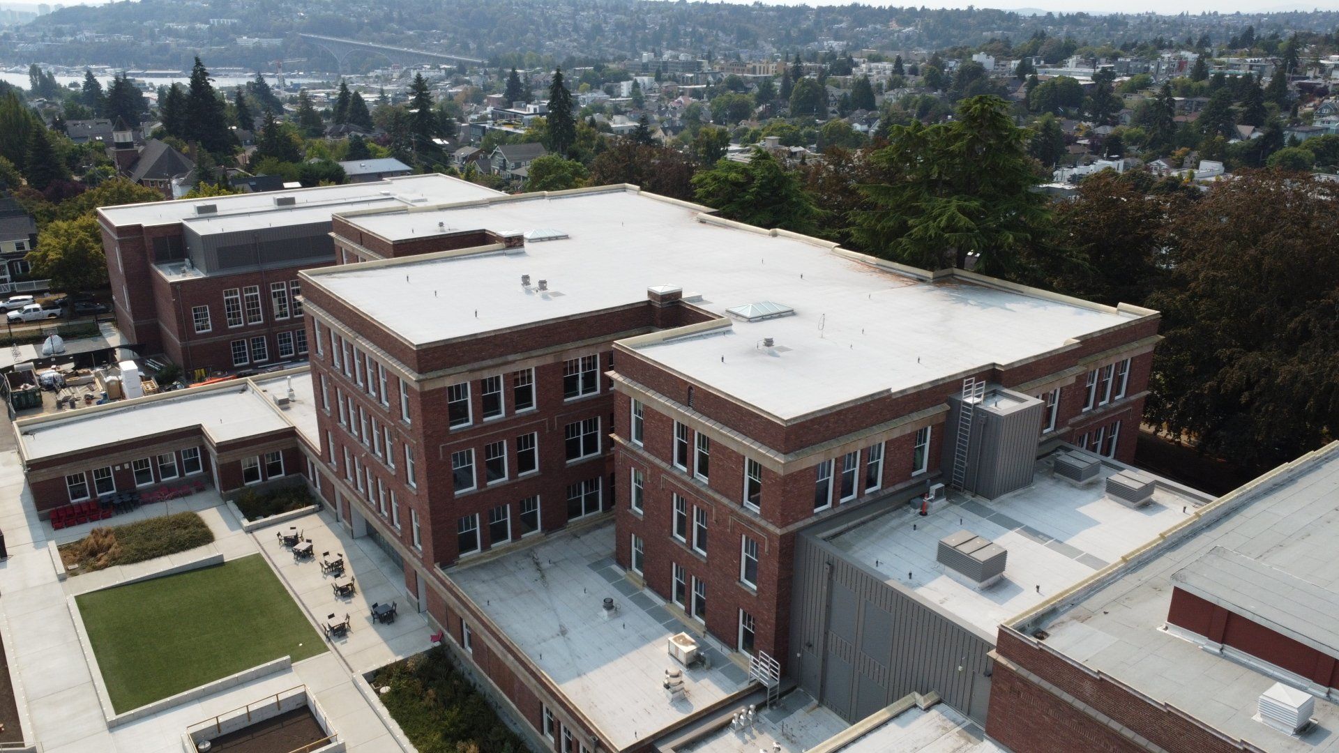 An aerial view of a large brick building with a white roof