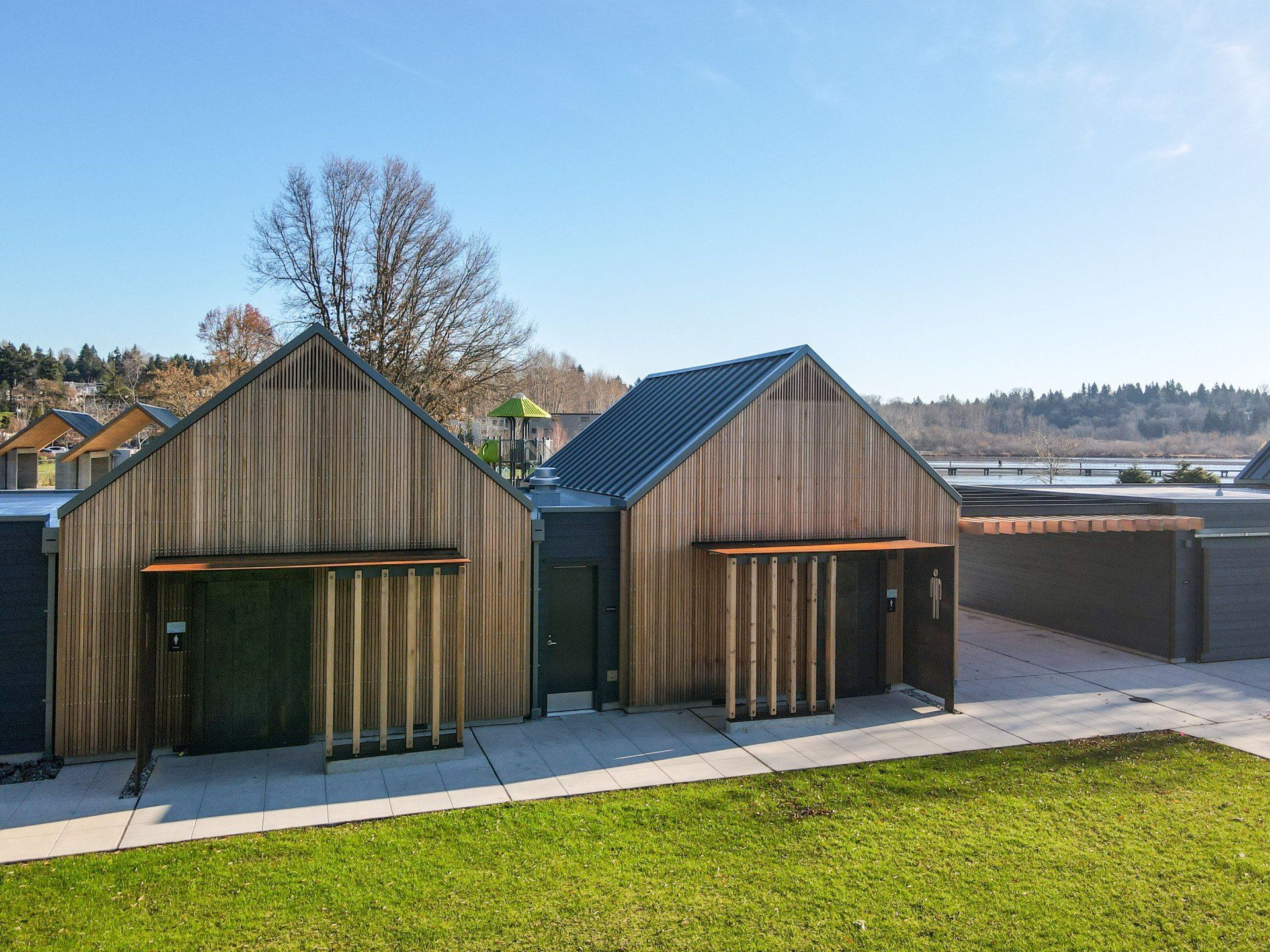 A wooden house with a black roof is sitting on top of a lush green field.