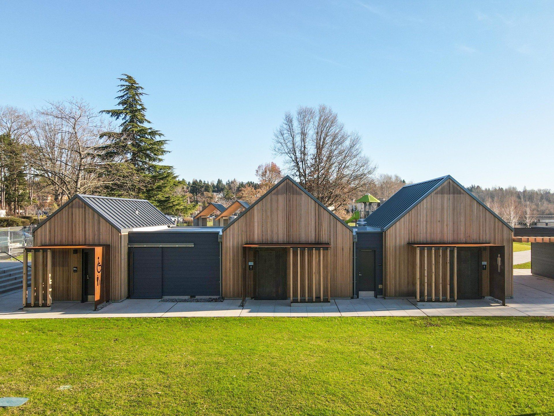 A row of wooden houses sitting next to each other on top of a lush green field.