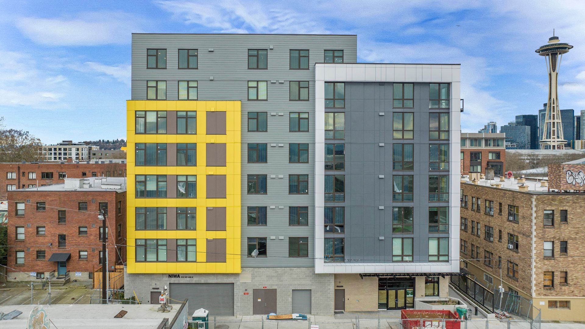 A large building with a lot of windows is surrounded by other buildings in a city.