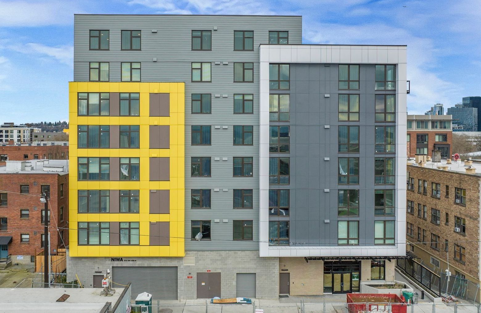 A large building with a lot of windows and a yellow building in the middle